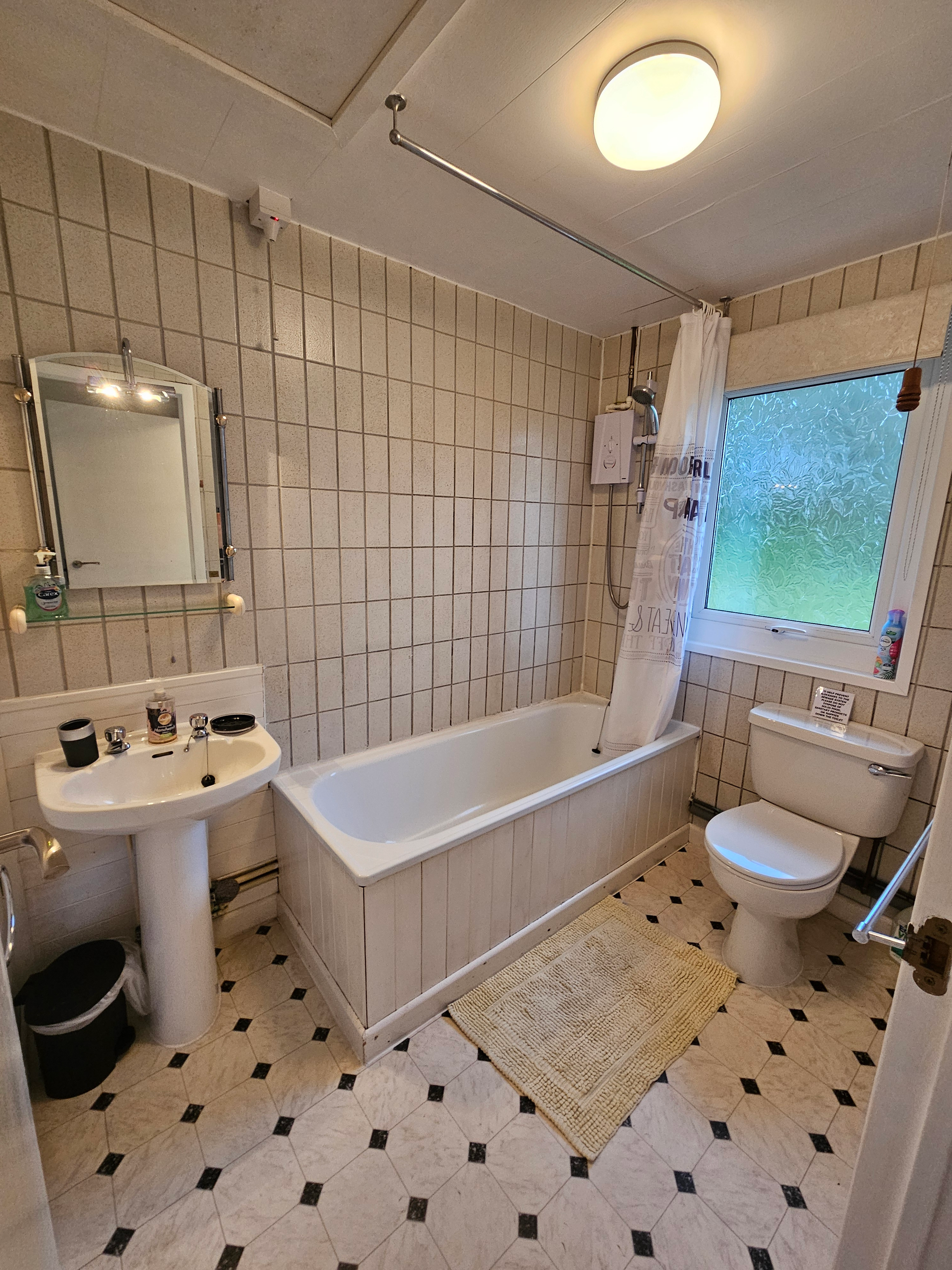 The full bathroom, has a toilet, bath/shower, sink and mirror