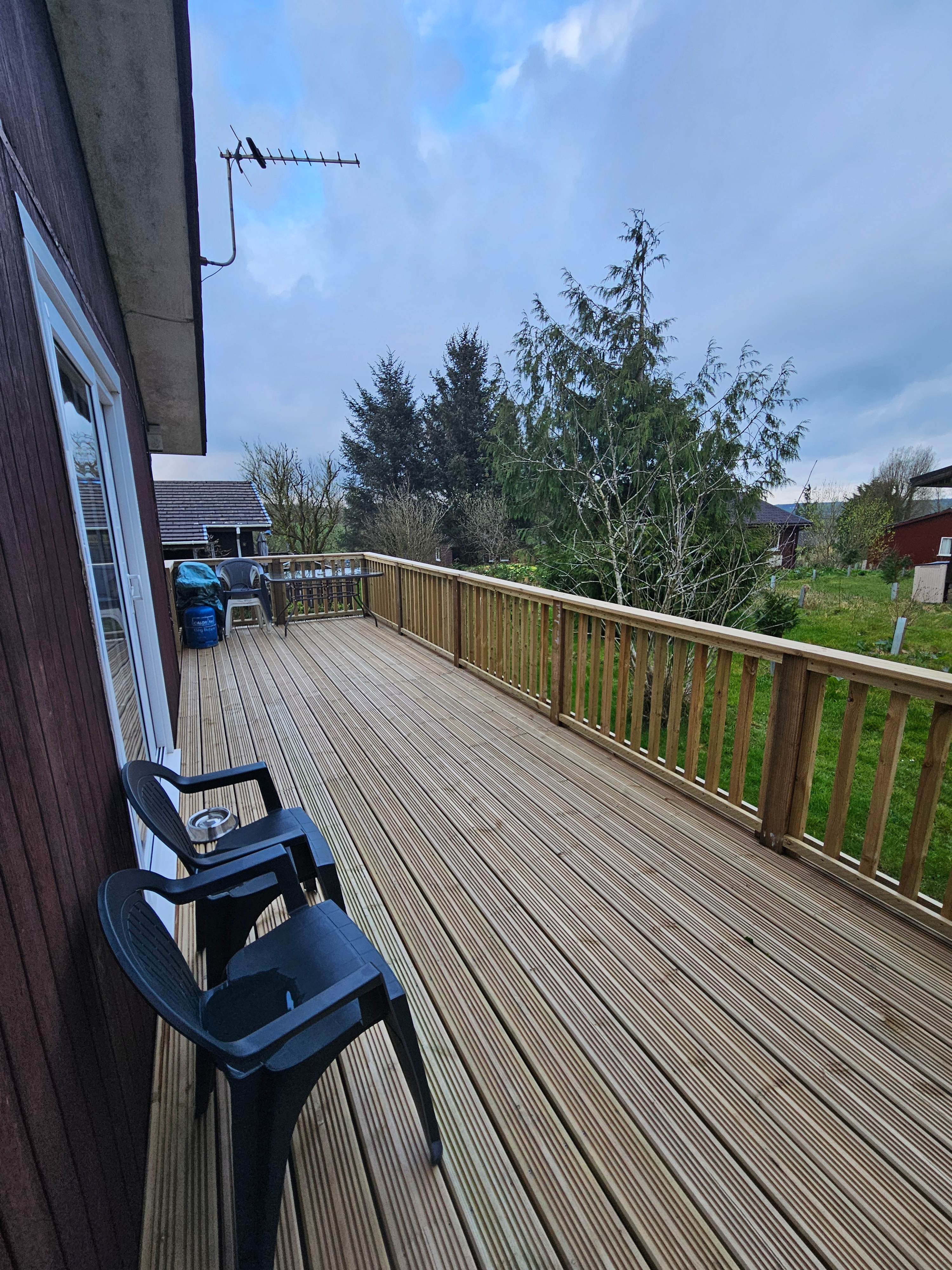 The decking which has a large table and BBQ set on, with views of nature and the lodge park